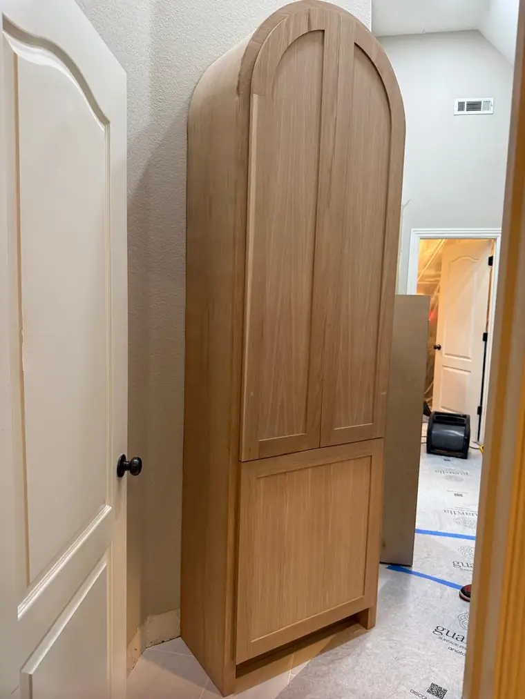 Arched-top white oak cabinet built into a hallway alcove