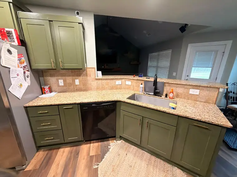 Olive cabinets with a corner sink and gold granite countertop