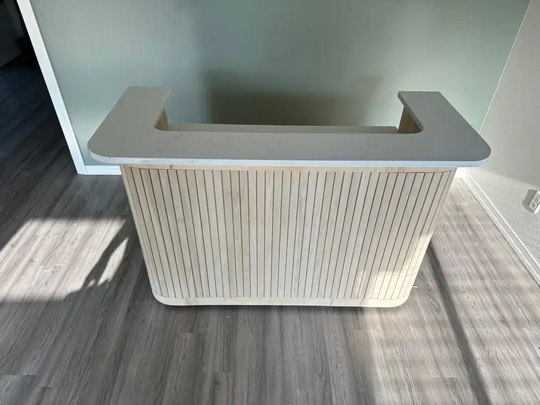 Finished reception desk with a fluted maple front and quartz top