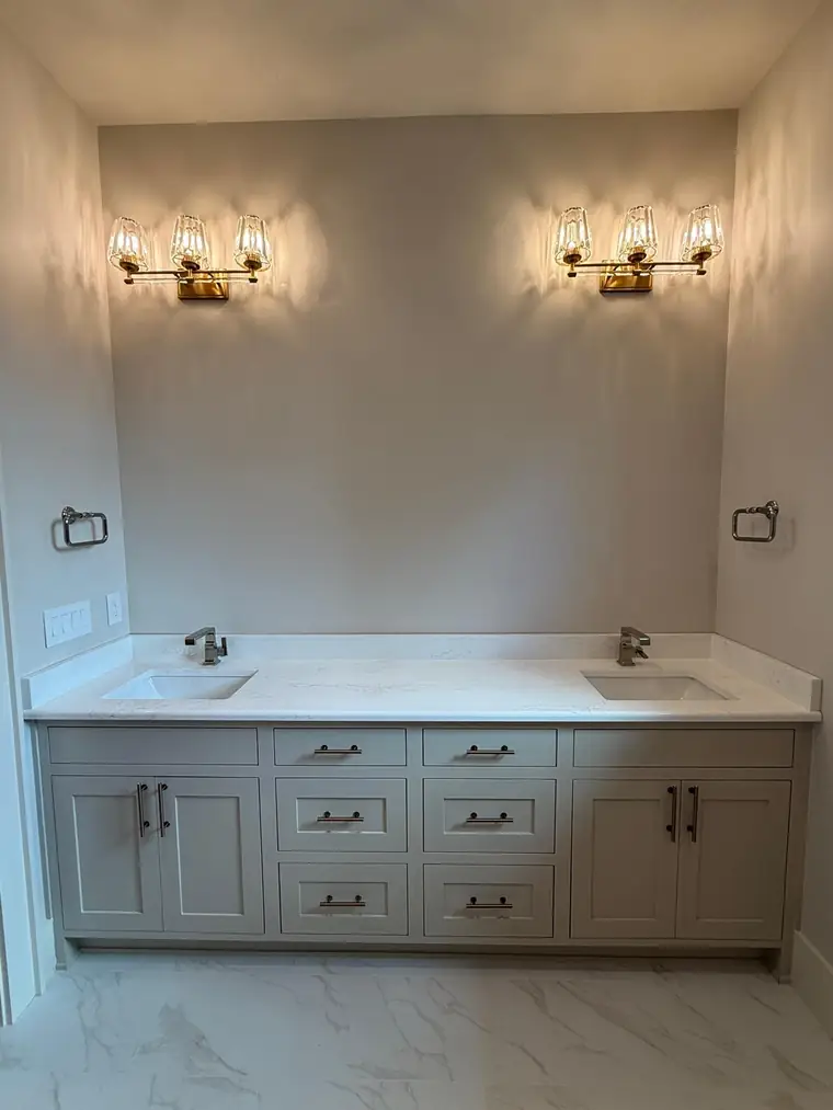 White double vanity with quartz top and brass sconce lighting